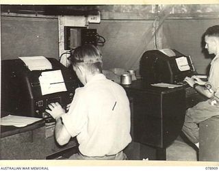 LAE AREA, NEW GUINEA. 1945-02-06. VX125507 SIGNALLER J. SAXON (1) AND VX112971 SERGEANT G.J. WALSH (2) OPERATING TELEPRINTER MACHINES AT THE SIGNALS TRANSMITTING CENTRE, 19TH LINES OF COMMUNICATION ..