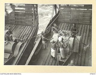 LAE, NEW GUINEA. 1944-10-27. NATIVES PREPARING A LOAD OF STORES ABOARD A LANDING BARGE FOR THE SHIPS WINCHES DURING THE LOADING OF THE EQUIPMENT OF THE 14/32ND INFANTRY BATTALION ABOARD THE ..