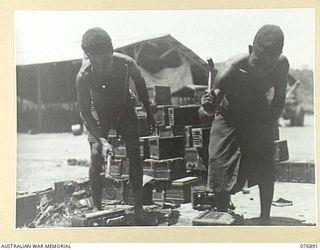 LAE, NEW GUINEA. 1944-11-15. THESE AUSTRALIAN NEW GUINEA ADMINISTRATIVE UNIT NATIVES ARE SMASHING UP UNSERVICEABLE BATTERY CASES IN THE SALVAGE SECTION OF THE BATTERY RECLAMATION WORKSHOPS, 2/7TH ..