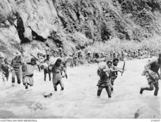 Ramu Valley, New Guinea. October 1943. Australian troops and native bearers fording the Ramu River in their advance up the Ramu Valley towards Lae