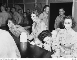 RABAUL, NEW BRITAIN, 1945-12-21. CAPTAIN H. WITT, OFFICER COMMANDING AUSTRALIAN ARMY MEDICAL WOMEN'S SERVICE (AAMWS), AND MEMBERS OF THE STAFF, SERVING REFRESHMENTS TO GUESTS AT THE OFFICIAL ..