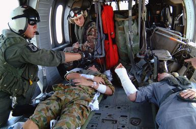 A US Navy (USN) air crewman (left) aboard an USN MH-60S Seahawk helicopter, Helicopter Combat Support Squadron 5 (HC-5), Andersen Air Force Base (AFB), Guam, makes final preparations for take-off as CHIEF Hospital Corpsman (HMC) Patrick Nardulli (rear, seated), monitors his patients. The USN helicopter crew, embarked on the Military Sealift Command (MSC) combat stores ship USNS NIAGARA FALLS (T-AFS 3) [not shown], accompanied by medical personnel assigned to the MSC hospital ship USNS MERCY (T-AH 19) [not shown], evacuated the two survivors of the April 2, 2005 crash of a Royal Australian Navy (RAN) Sea King helicopter in Nias, Indonesia