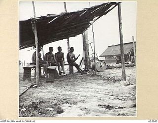 BORAM BEACH, WEWAK AREA, NEW GUINEA. 1945-08-31. MEMBERS OF 8 INFANTRY BRIGADE IN THE TENNIS COURT SHED WAITING FOR THEIR TURN TO PLAY. IDENTIFIED PERSONNEL ARE:- CAPTAIN J.J.F. MCCARTHY (1); ..