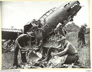 1943-09-25. NEW GUINEA. FALL OF LAE. AUSTRALIAN TROOPS INSPECT A SMASHED JAPANESE PLANE ON THE AIRSTRIP AT LAE