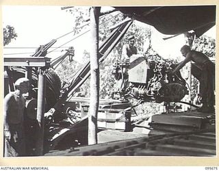 BOUGAINVILLE. 1945-08-30. PERSONNEL OF 2/4 ARMOURED REGIMENT WORKSHOP, LOWERING AN ENGINE INTO THE HULL OF A TANK AFTER REPAIRS. CRANES ARE USED TO REMOVE MOTORS TO FACILITATE REPAIR WORK