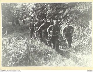 Karkar Island, New Guinea. 1944-06-04. Members of the Vickers machine gun crew of the 37/52nd Infantry Battalion moving into position on the island. Identified personnel are:- VX115994 Private J. ..