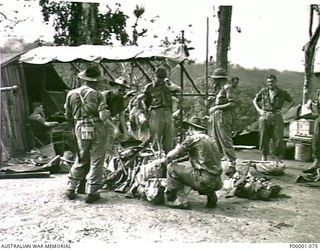 THE SOLOMON ISLANDS, 1945-03-27. A GROUP OF AUSTRALIAN SOLDIERS PREPARING TO LEAVE CAMP ON THE NUMA NUMA TRAIL ON BOUGAINVILLE ISLAND. (RNZAF OFFICIAL PHOTOGRAPH.)