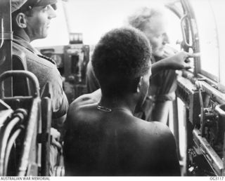 AIRBORNE OVER BOUGAINVILLE ISLAND, SOLOMON ISLANDS. 1945-07-28. NATIVE "BOYS" USED AS AIR OBSERVERS HAVE PROVED INVALUABLE. THE "BOY" IN THE FOREGROUND IS POINTING OUT JAPANESE POSITIONS TO FLIGHT ..