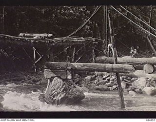 BULLDOG-WAU ROAD, NEW GUINEA, 1943-07-13. TROOPS OF HEADQUARTERS, ROYAL AUSTRALIAN ENGINEERS, 11TH AUSTRALIAN DIVISION, BRIDGING A MOUNTAIN STREAM AT THE 19 MILE POINT