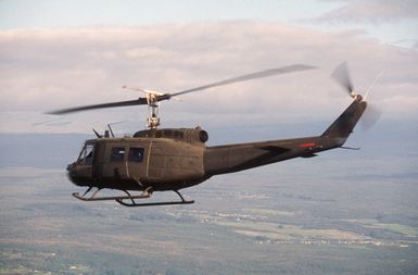 An air-to-air left side view of a UH-1 Iroquois helicopter of the 19th Air Cavalry, Hawaii Army National Guard, during Exercise OPPORTUNE JOURNEY 85-3
