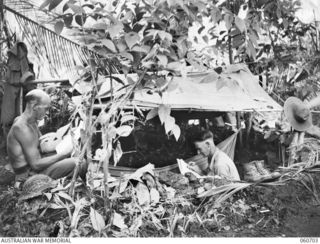 FINSCHHAFEN, NEW GUINEA. 1943-10-30. QX27880 PRIVATE W. C. HOLDER (LEFT) AND QX9110 PRIVATE F. N. CROSS OF GATTON, QLD, BOTH OF HEADQUARTERS, 26TH AUSTRALIAN INFANTRY BRIGADE RELAXING WHILE OFF ..