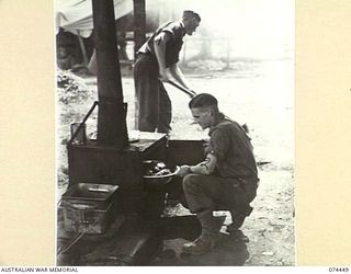 MADANG, NEW GUINEA. 1944-06-27. QX59510 PRIVATE K. RICHARDSON (1); AND QX49439 PRIVATE W.D. MCKAY (2) COOKS OF THE 5TH DIVISION RECEPTION CAMP PREPARING A MEAL IN THE UNIT COOKHOUSE