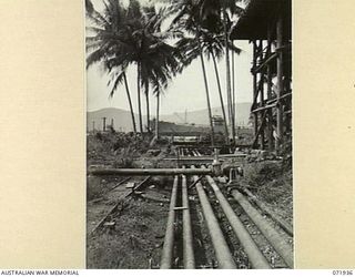 MILNE BAY, PAPUA, NEW GUINEA. 1944-04-03. PIPELINES FROM THE 2ND BULK PETROLEUM STORAGE COMPANY LEADING TO THE OIL TANKER 'EMPIRE SILVER', BERTHED AT THE BACKGROUND. THE FUEL IS PUMPED DIRECTLY ..