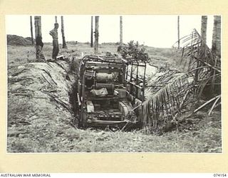 HANSA BAY, NEW GUINEA. 1944-06-19. A REAR VIEW OF A BURNT OUT JAPANESE ARMY 6 WHEEL TRUCK DUG IN, IN A BOMB BLASTED COCONUT PLANTATION. THIS VEHICLE WAS USED AS A RADIO VAN AND FOR CABLE LAYING ..