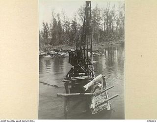 MOTUPENA POINT, BOUGAINVILLE ISLAND, 1945-01-26. TROOPS OF THE 23RD FIELD COMPANY, PLACING A STRINGER IN POSITION NEAR THE UNIT PILE DRIVER AND CRANE WORKING FROM THE NORTH SIDE OF THE JABA RIVER ..