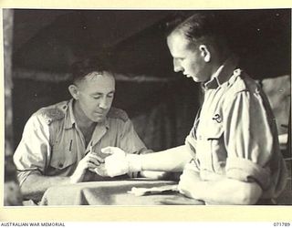 WAREO, PAPUA, NEW GUINEA, 1944-03-29. WX11047 CAPTAIN A. A. MERRITT (LEFT), COMMANDING OFFICER, B COMPANY, 4TH FIELD AMBULANCE, TREATING VX147298 SAPPER R. J. ROBBINS, AT THE REGIMENTAL AID POST