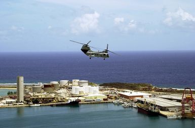 A US Navy (USN) CH-46 Sea Knight helicopter assigned to Helicopter Combat Support Squadron Five (HC-5), makes it's final flight over the harbor and dock area at Andersen Air Force Base (AFB), Guam. HC-5 is replacing its inventory of Sea Knight helicopters with Black Hawk helicopters