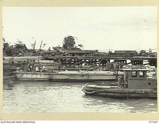 LAE, NEW GUINEA. 1944-03-23. LOOKING TOWARDS SALAMUA FROM THE WATERSIDE AT HEADQUARTERS LAE BASE SUB-AREA, SHOWING THE NEW WHARF AND SHIPPING IN THE FOREGROUND WITH THE ROYAL AUSTRALIAN NAVY ..