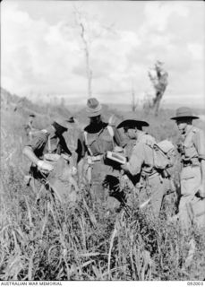 WEWAK POINT, NEW GUINEA, 1945-05-12. LIEUTENANT-COLONEL G.S. COX, COMMANDING OFFICER 2/4 INFANTRY BATTALION (2), CHECKING OVER A MAP WITH HIS OFFICERS. IN THE BACKGROUND STANDS LIEUTENANT-COLONEL ..