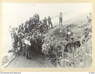 QX6239 Major E. G. Green, Officer Commanding B Company, 37/52nd Infantry Battalion, uses a sand model to outline to his officers, NCOs and men the method of attack against Karkar Island