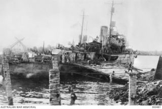 ALEXISHAFEN, NEW GUINEA. 1944-04. HMAS BUNDABERG (J231) SECURED ALONGSIDE REMNANTS OF ALEXISHAFEN WHARF AFTER DISEMBARKING TROOPS AND AMMUNITION TO ASSIST IN THE CAPTURE OF SEK ISLAND. NOTE THE 20 ..