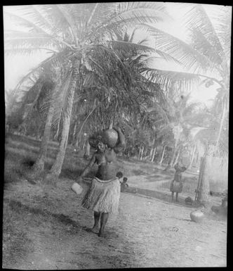 Woman wearing a grass skirt and carrying a pot on her shoulder, Port Moresby, Papua, ca. 1923, 2 / Sarah Chinnery