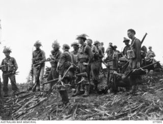 BOUGAINVILLE ISLAND, NEW BRITAIN. 1944-12-30. PERSONNEL OF A COMPANY, 25TH INFANTRY BATTALION, WITH THEIR SUPPORT WEAPONS, WAITING TO MOVE OFF DURING THE ATTACK ON JAPANESE POSITIONS ON PEARL RIDGE ..