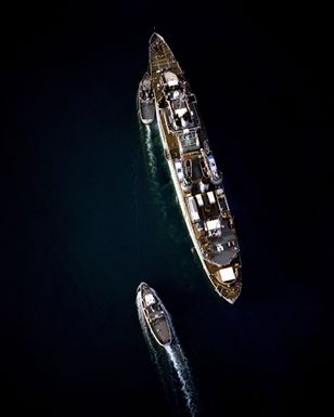 An overhead view of harbor tugs assisting the repair ship USS JASON (AR 8) into port