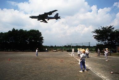 Japanese civilians pause during a game to watch a B-52G Stratofortress aircraft pass overhead. The 43rd Bombardment Wing aircraft flew to Japan from Andersen Air Force Base, Guam, for the annual Japanese-American Friendship Festival