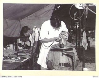 JACQUINOT BAY, NEW BRITAIN, 1945-06-16. PTE E. HANNAFORD, 154 WATERCRAFT WORKSHOP (3), RECEIVING TREATMENT FROM MAJ R.A. PICKFORD, COMMANDING OFFICER, 77 DENTAL UNIT (AIF) (2). PTE M.K. BARTEN (1) ..