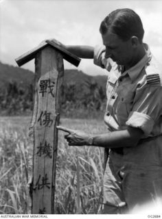 BUT AREA, DAGUA, NORTH EAST NEW GUINEA. C. 1945-04. A RAAF OFFICER INSPECTING A GUIDE POST ON A SECTION OF THE DAGUA AIRFIELD WHICH DENOTES IN JAPANESE KANJI CHARACTERS A "SUPPLIES AREA FOR THE WAR ..