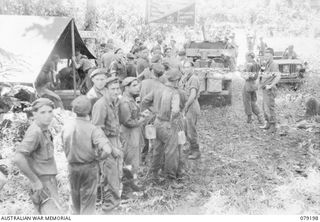 BOUGAINVILLE ISLAND. 1945-02-17. TROOPS OF C COMPANY, 61ST INFANTRY BATTALION RESTING AT THE YOUNG MEN'S CHRISTIAN ASSOCIATION - AUSTRALIAN COMFORTS FUND JEEP AT MEIVO JUNCTION AFTER THEY HAD ..