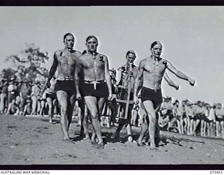 LAE. NEW GUINEA. 1944-08-27. THE REST AND RECREATION TEAM FROM THE TRANSPORT SECTION, HEADQUARTERS, 5TH DIVISION, CARRY THE REEL OFF THE BEACH AT THE CONCLUSION OF THE SURF LIFESAVING EVENT AT THE ..