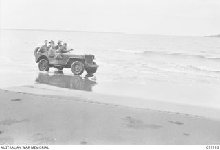 POTSDAM-HANSA BAY AREA, NEW GUINEA. 1944-07-30. PERSONNEL OF HEADQUARTERS, 8TH INFANTRY BRIGADE DRIVING ALONG THE BEACH IN THEIR JEEP. OWING TO THE BAD ROADS AND TRACKS IN THIS AREA WHEREVER ..