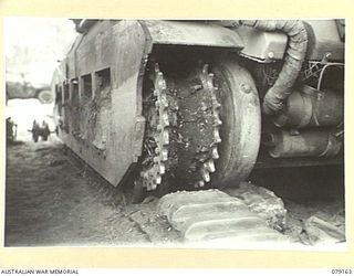 TOROKINA, BOUGAINVILLE ISLAND. 1945-02-21. A REAR DRIVING SPROCKET OF A "MATILDA" TANK OF B SQUADRON, 2/4TH ARMOURED REGIMENT, PACKED WITH CORAL MUD. THIS TENACIOUS MUD EXPANDS THE TRACKS OF THE ..