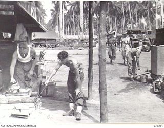 MADANG, NEW GUINEA. 1944-08-15. COOKS OF A PLATOON, 165TH GENERAL TRANSPORT COMPANY PREPARING A MEAL IN THE UNIT KITCHEN. THE PLATOON FITTER'S WORKSHOPS AND TENT LINES CAN BE SEEN IN THE ..