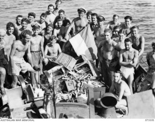 KARKAR ISLAND, NEW GUINEA. 1944-05-18. MEMBERS OF THE CREW ABOARD HMA MOTOR LAUNCH 431 DISPLAYING A CAPTURED JAPANESE MARINE FLAG. THEY ARE GATHERED AT THE STERN OF THE VESSEL AROUND EMPTY ..