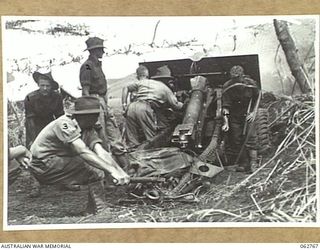 RAMU VALLEY, NEW GUINEA. 1943-12-25. MEMBERS OF NO. 8 BATTERY, 2/4TH FIELD REGIMENT ALL TAKING TURNS TO SEND OVER TWO ROUNDS OF 25 POUNDER SHELLS SIGNED "MERRY CHRISTMAS" INTO THE JAPANESE LINES AS ..