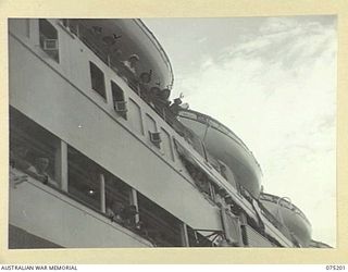 LAE, NEW GUINEA. 1944-08-14. MEMBERS OF THE STAFF OF THE 2/1ST HOSPITAL SHIP MANUNDA LOOKING OVER THE VESSELS SIDE AS MEMBERS OF THE AUSTRALIAN ARMY NURSING SERVICE (AANS) FROM THE 128TH GENERAL ..