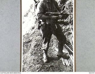 SHAGGY RIDGE, NEW GUINEA. 1943-12-27. WX4252 WARRANT OFFICER II, R.E. JONES OF THE 2/16TH AUSTRALIAN INFANTRY BATTALION, 21ST AUSTRALIAN INFANTRY BRIGADE, CHECKS THE MAGAZINE OF HIS OWEN GUN BEFORE ..