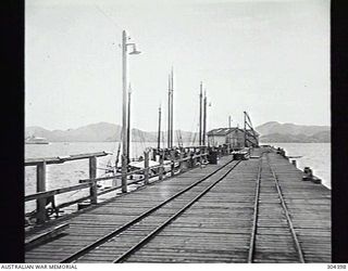 PORT MORESBY, PAPUA. 1932-09-17. THE PIER, LOOKING SEAWARDS. NOTE THE COUNTY CLASS CRUISER IN THE LEFT BACKGROUND. (NAVAL HISTORICAL COLLECTION)