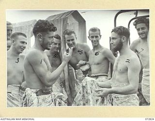 MADANG, NEW GUINEA, 1944-04-30. PERSONNEL FROM HMA MOTOR LAUNCHES 816 AND 424, ABOARD HMA MOTOR LAUNCH 424 ARGUING IN FRIENDLY FASHION THE LENGTH OF A PIECE OF BRIGHTLY COLOURED JAPANESE CLOTH ..