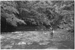 Young man holding something by a river