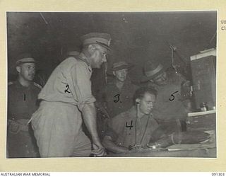BOUGAINVILLE. 1945-04-27. MAJOR-GENERAL C.H. SIMPSON, SIGNAL OFFICER- IN- CHIEF (2), WATCHING SIGNALMAN D.N. MALONEY (4), AT WORK IN THE SIGNAL SECTION, 15 INFANTRY BRIGADE, DURING A TOUR OF ..
