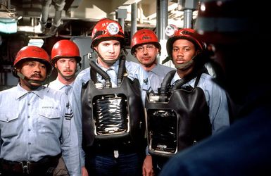 Members of a firefighting team, some wearing oxygen breathing apparatuses, stand ready for a drill aboard the amphibious assault ship USS GUAM (LPH 9)