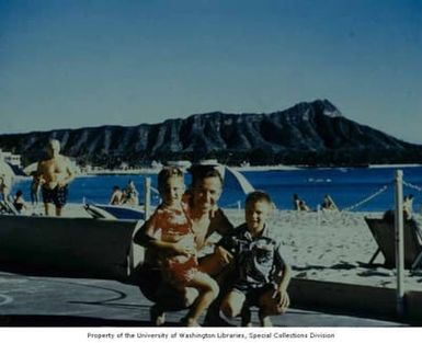 Congressman Henry M. Jackson posing with two unidentified children for a photograph, with Diamond Head in the background, on Waikiki Beach, Oahu, Hawaii, approximately 1950s