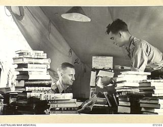 KILIGIA, NEW GUINEA. 1944-04-04. NX114455 SERGEANT B.J. LOCKE (2), AT ARMY EDUCATION SERVICE, HEADQUARTERS 5TH DIVISION, RECEIVING ASSISTANCE FROM QX28779 SERGEANT P.J. HORAN (1), IN SELECTING A ..