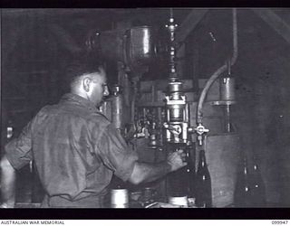 RABAUL, NEW BRITAIN, 1946-03-29. SERGEANT J. DOOKES OPERATING A BOTTLING AND FILLING MACHINE AT THE AUSTRALIAN ARMY CANTEENS SERVICE CORDIAL FACTORY. THE FACTORY, STAFFED BY SEVEN SKILLED ARMY ..