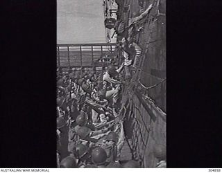 1944-09. NEW GUINEA. US INFANTRY USING LANDING NETS TO TRANSFER BETWEEN THE LANDING SHIP INFANTRY LARGE HMAS MANOORA AND A LANDING CRAFT IN THE COURSE OF TRAINING PRIOR TO THE MOROTAI LANDING. ..