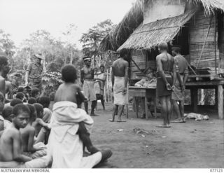 LAE, NEW GUINEA. 1944-11-27. AN OFFICER OF THE AUSTRALIAN NEW GUINEA ADMINISTRATIVE UNIT ACTING AS MAGISTRATE AFTER SETTING UP COURT IN BUTIBUM VILLAGE TO TRY A NATIVE OFFENDER. THIS VILLAGE WAS ..